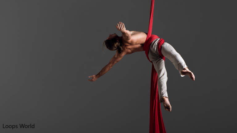 Aerialist posing on red aerial silks